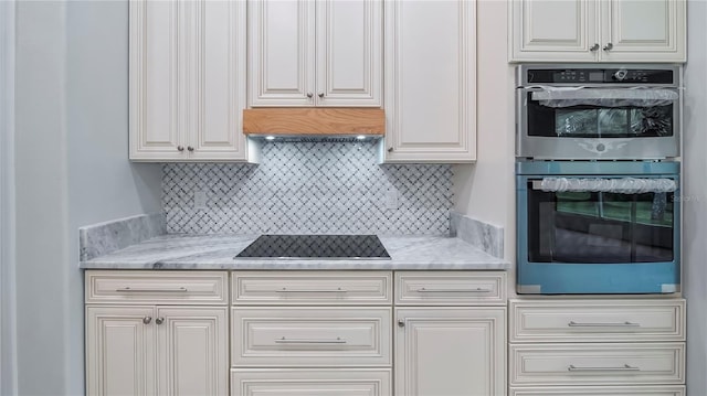 kitchen with double oven, light stone counters, black electric stovetop, and white cabinets