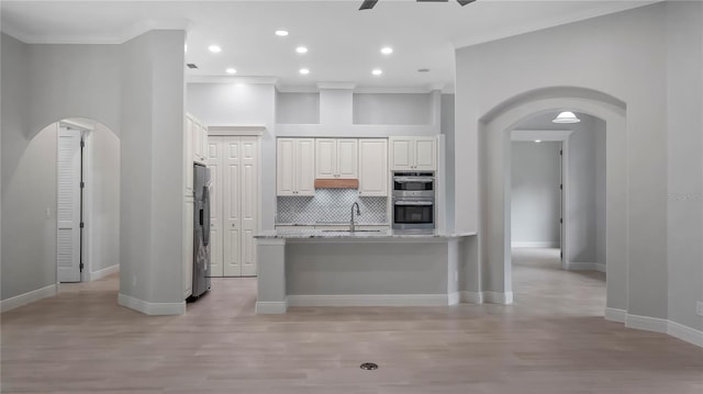 kitchen featuring appliances with stainless steel finishes, light stone countertops, crown molding, and light hardwood / wood-style floors