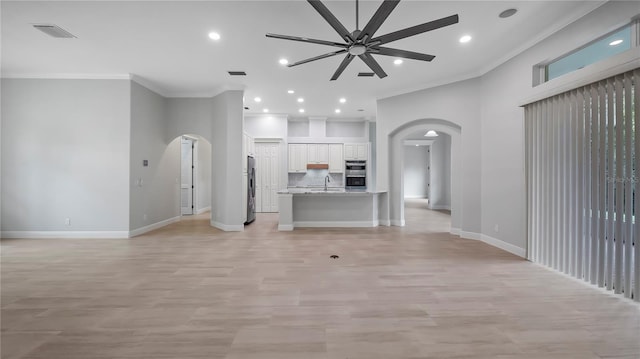 unfurnished living room featuring crown molding, sink, and ceiling fan