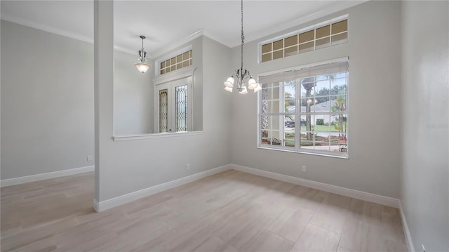 empty room with light hardwood / wood-style flooring, ornamental molding, and an inviting chandelier