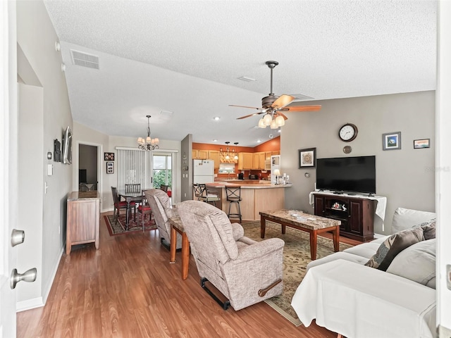 living room featuring ceiling fan with notable chandelier, hardwood / wood-style flooring, and a textured ceiling