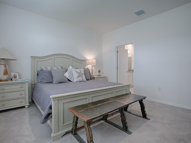 bedroom with light colored carpet and ensuite bath