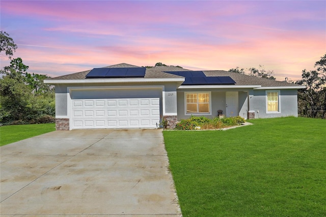 view of front of property with a garage, solar panels, and a lawn