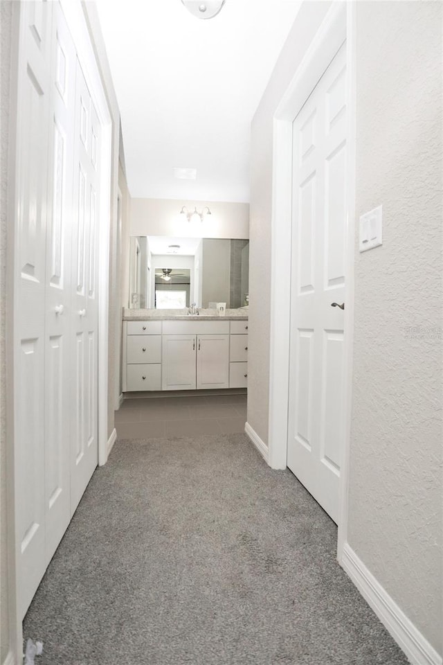 corridor featuring sink and light carpet