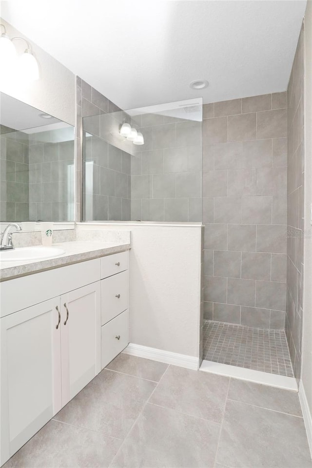 bathroom with vanity, tile patterned flooring, and tiled shower