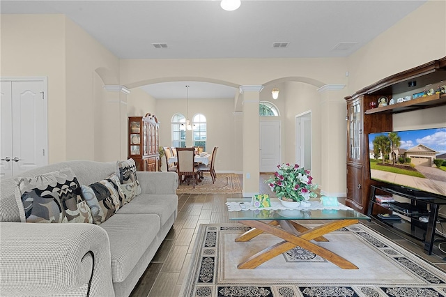 living room featuring ornate columns and a notable chandelier