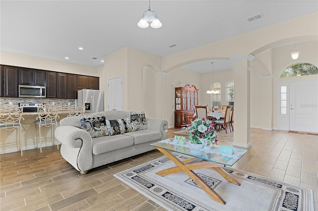 living room featuring decorative columns and a notable chandelier