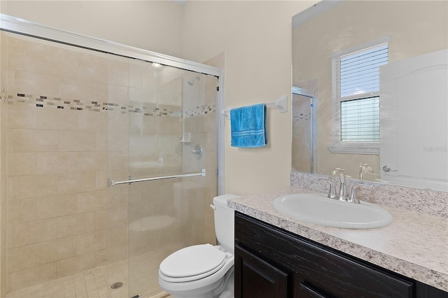 bathroom featuring vanity, toilet, and a shower with shower door