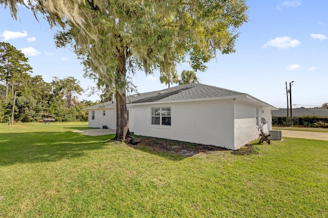 view of side of property with a patio, a yard, and central AC unit