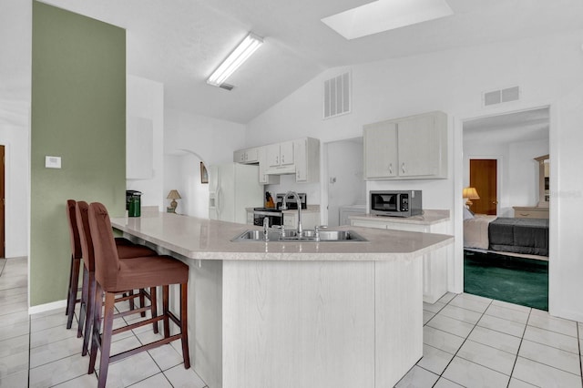 kitchen featuring kitchen peninsula, white cabinetry, lofted ceiling with skylight, sink, and white refrigerator with ice dispenser