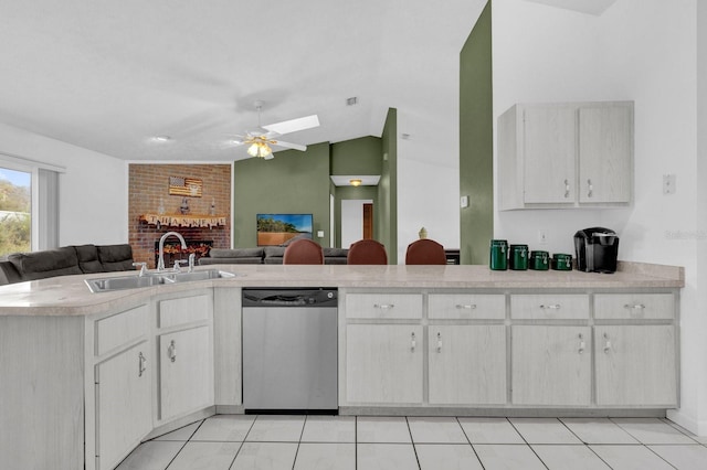 kitchen featuring sink, dishwasher, kitchen peninsula, vaulted ceiling with skylight, and light tile patterned floors