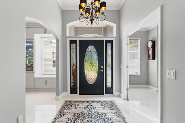 entrance foyer with light tile patterned flooring, ornamental molding, and an inviting chandelier