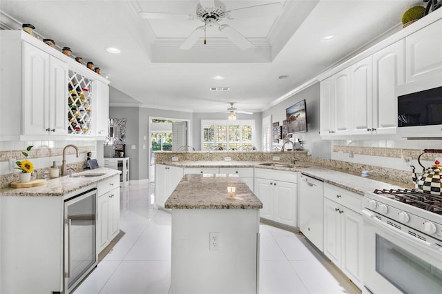 kitchen featuring white appliances, sink, a center island, kitchen peninsula, and beverage cooler