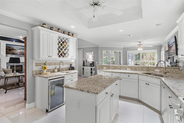 kitchen with wine cooler, sink, kitchen peninsula, and white cabinets