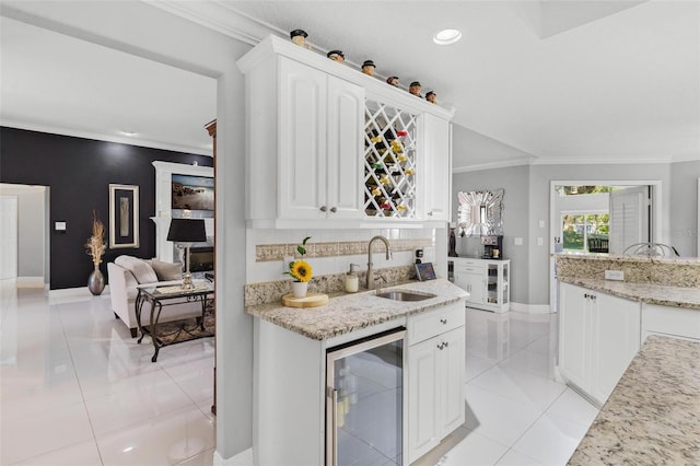 kitchen with wine cooler, white cabinetry, light stone countertops, light tile patterned flooring, and sink