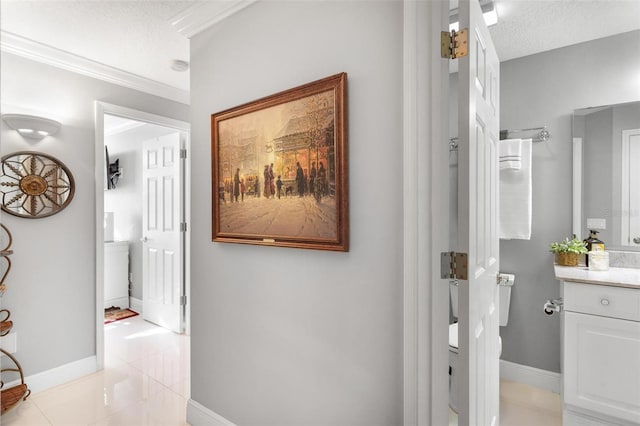 corridor featuring crown molding, a textured ceiling, and light tile patterned floors