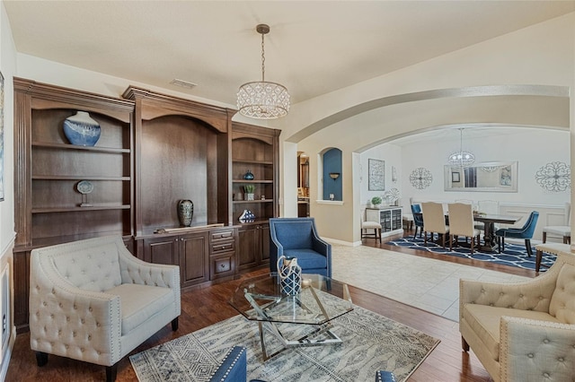 living room featuring a notable chandelier, dark hardwood / wood-style flooring, and built in features