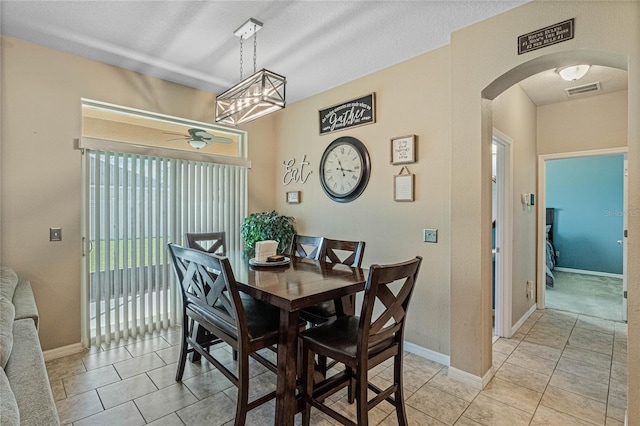 tiled dining room with ceiling fan and a textured ceiling