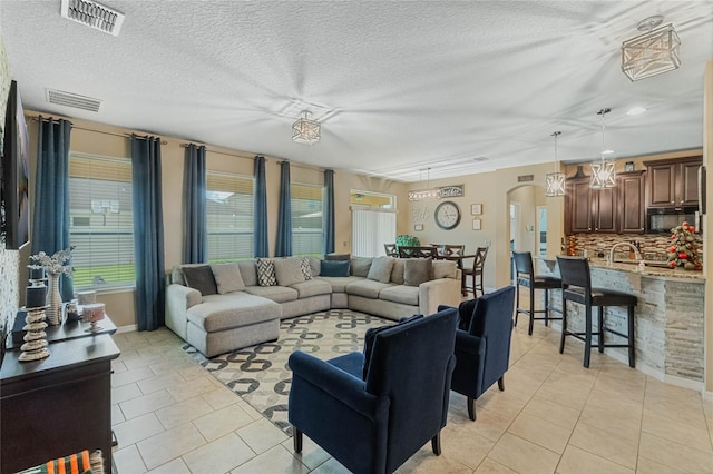 living room featuring sink, light tile patterned floors, and a textured ceiling