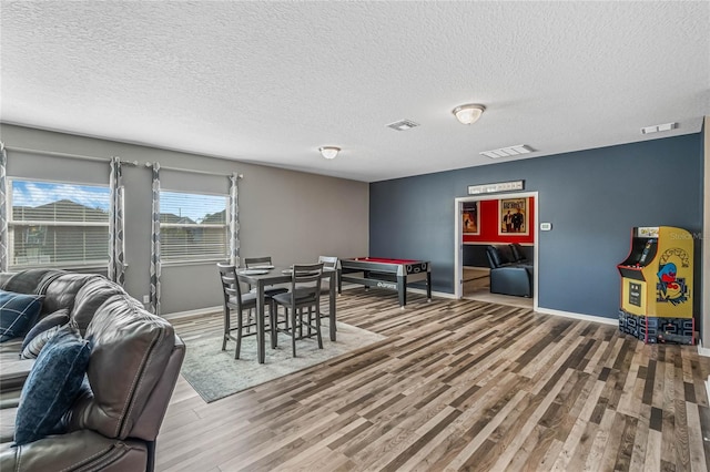 dining room featuring wood-type flooring and a textured ceiling