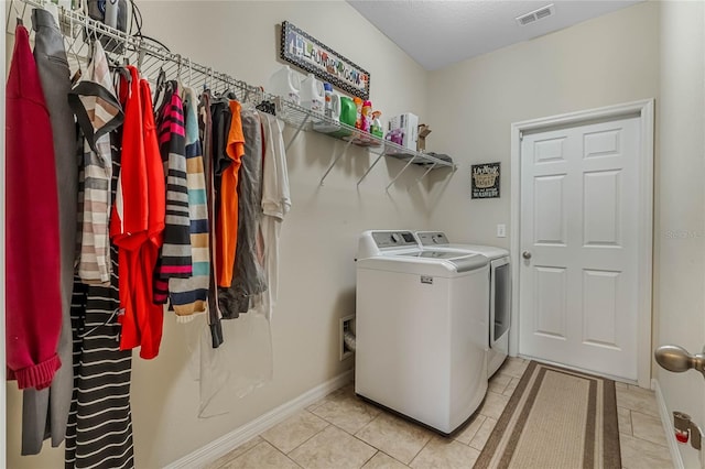 laundry room with light tile patterned flooring and washer and clothes dryer