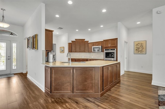 kitchen featuring decorative backsplash, dark hardwood / wood-style floors, stainless steel appliances, sink, and decorative light fixtures