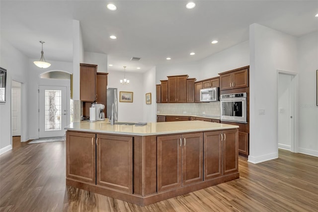 kitchen featuring appliances with stainless steel finishes, kitchen peninsula, dark hardwood / wood-style floors, and hanging light fixtures