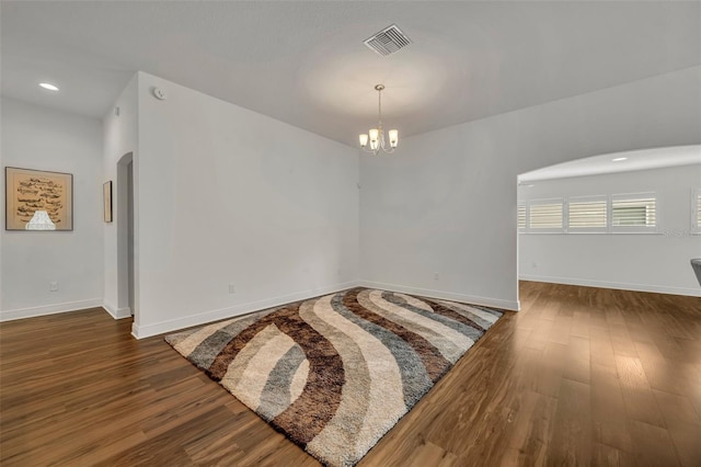 unfurnished room with a notable chandelier and dark hardwood / wood-style flooring