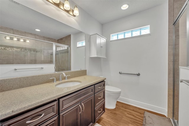 bathroom featuring toilet, walk in shower, vanity, and wood-type flooring