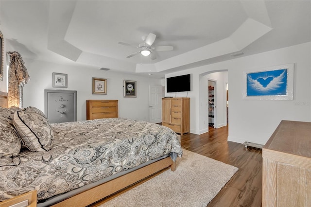 bedroom featuring dark wood-type flooring, ceiling fan, a raised ceiling, and a spacious closet