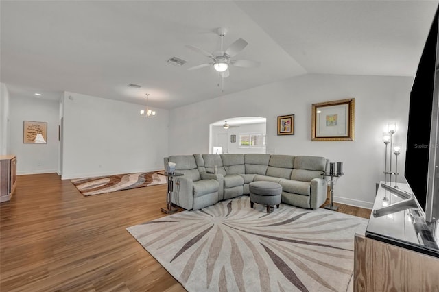 living room with lofted ceiling, ceiling fan with notable chandelier, and light wood-type flooring