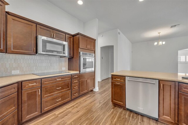 kitchen featuring a notable chandelier, appliances with stainless steel finishes, decorative light fixtures, and light wood-type flooring