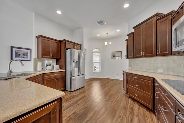 kitchen featuring tasteful backsplash, sink, pendant lighting, light hardwood / wood-style floors, and stainless steel appliances