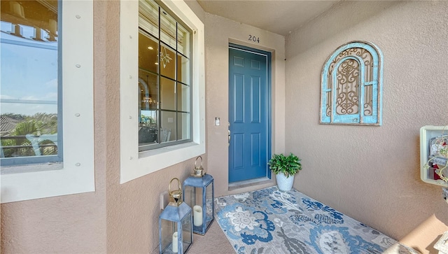 view of exterior entry with stucco siding and covered porch