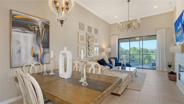 dining area with light tile patterned floors, a glass covered fireplace, baseboards, a notable chandelier, and a towering ceiling