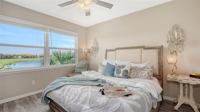 bedroom featuring hardwood / wood-style floors, a water view, and ceiling fan