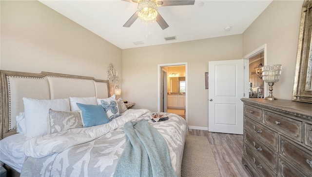 bedroom featuring ensuite bath, a ceiling fan, visible vents, baseboards, and wood finished floors