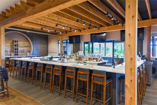 bar featuring wood-type flooring and rail lighting