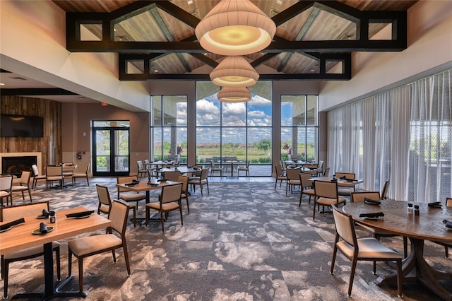 carpeted dining room with a towering ceiling, wood ceiling, and a fireplace