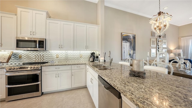 kitchen with appliances with stainless steel finishes, decorative light fixtures, white cabinetry, sink, and light stone countertops