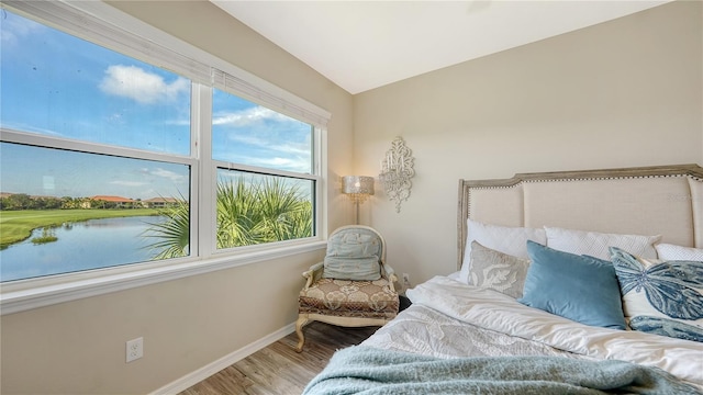 bedroom featuring hardwood / wood-style floors and a water view