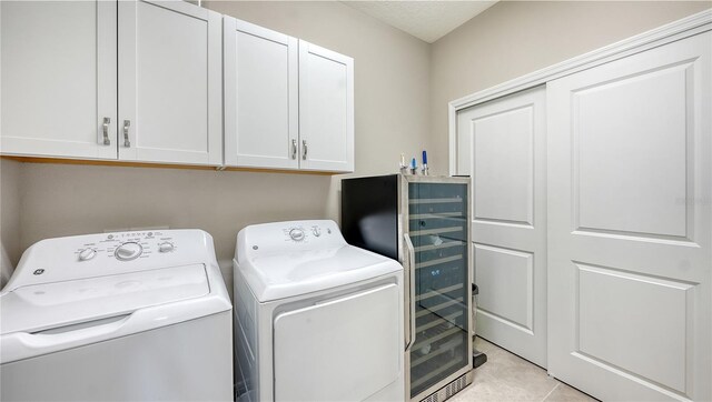 clothes washing area with cabinets, light tile patterned floors, beverage cooler, and independent washer and dryer