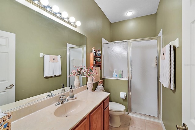 bathroom featuring a shower with door, vanity, tile patterned floors, and toilet