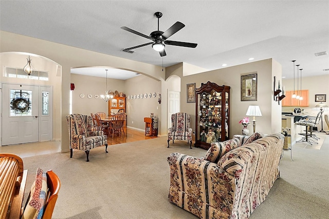 living room with ceiling fan with notable chandelier and light colored carpet