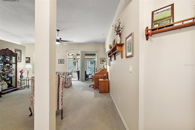 corridor with light carpet and a textured ceiling