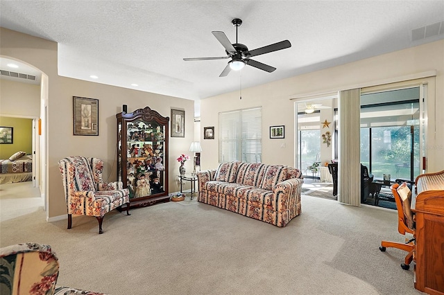 carpeted living room with ceiling fan and a textured ceiling