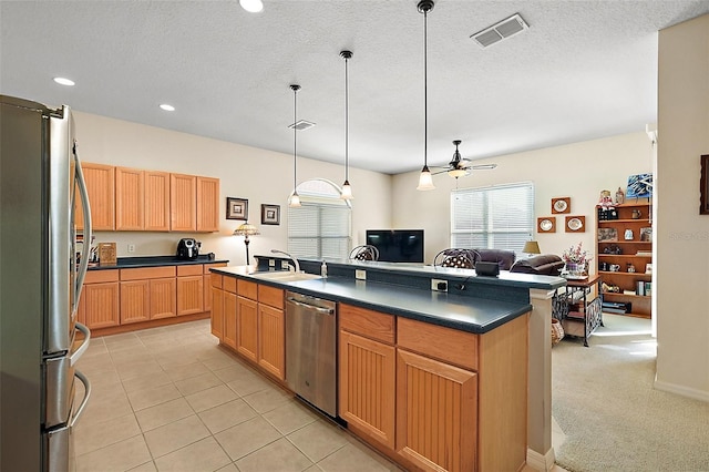 kitchen with sink, a center island with sink, a textured ceiling, appliances with stainless steel finishes, and pendant lighting