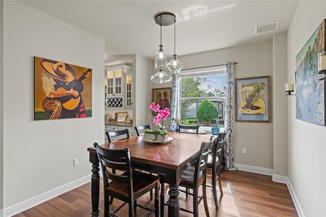 dining area featuring a textured ceiling and hardwood / wood-style floors