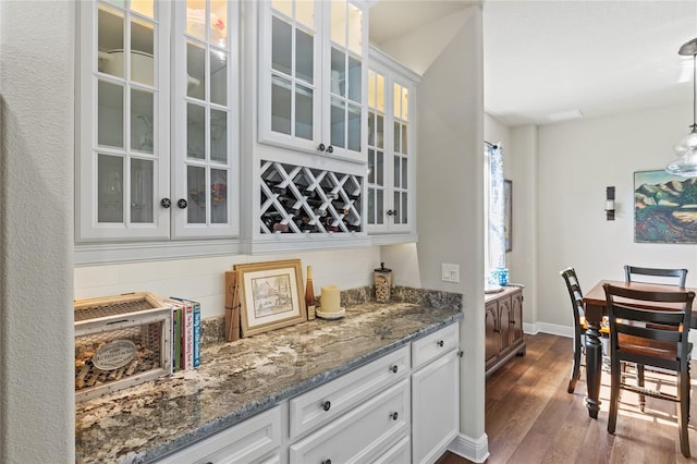 bar featuring white cabinets, pendant lighting, light stone counters, and dark hardwood / wood-style floors