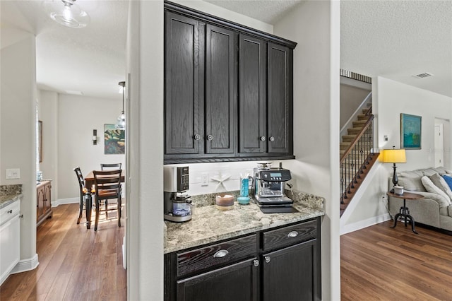 kitchen featuring a textured ceiling, light stone counters, and dark hardwood / wood-style floors